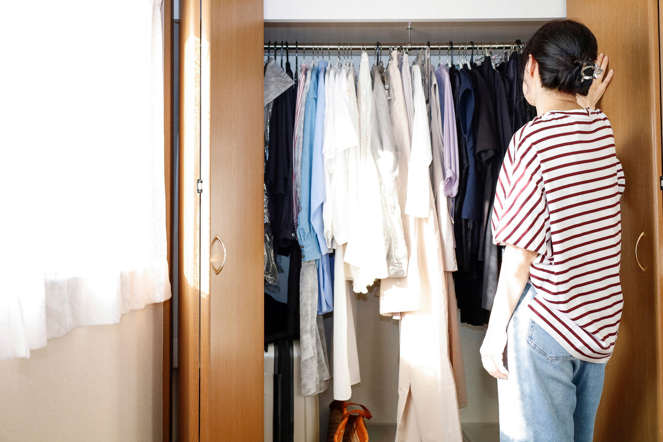 クローゼットを開けて服を眺める女性の後ろ姿